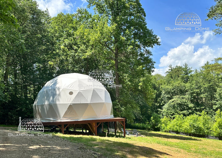 29.5-foot (9-meter) geodesic dome tent by Glamping Dome Store, perfect for Airbnb, B&B, or glamping site setups. Located at Big Little Clouds in Charlotte, North Carolina, USA, this white dome tent is elevated on a wooden platform amidst a serene forested landscape, offering a unique and eco-friendly accommodation option.