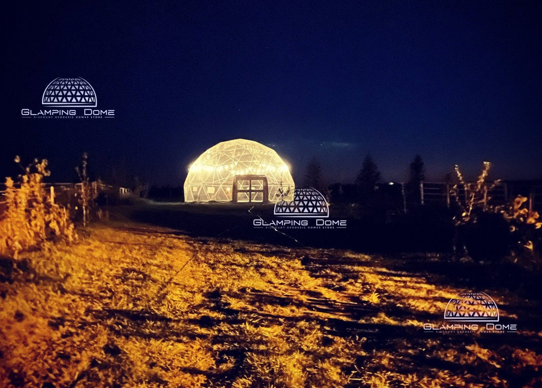 A stunning 32-foot (10-meter) illuminated geodesic dome tent glowing at night in Cypress Hills, Alberta, Canada. The dome, a project by Glamping Dome Store, is set amidst a serene outdoor environment, showcasing its elegance and practicality for unique events and gatherings.