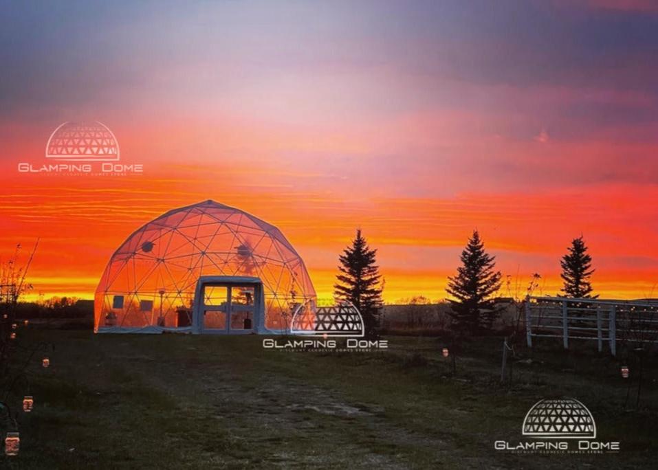 A 32-foot (10-meter) transparent PVC geodesic dome tent with a double door, located in Cypress Hills, Alberta, Canada. This Glamping Dome Store project stands beautifully under the night sky, offering a warm and inviting space for weddings, social gatherings, corporate events, and holiday setups, combining durability and charm in a serene outdoor setting.