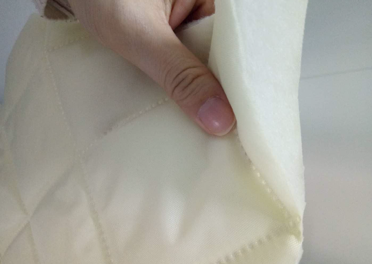 Close-up of the cream-colored Quilted Synthetic Insulation Fabric Layer by Glamping Dome Store, showcasing its quilted design and multi-layered structure. This durable fabric is available in two thickness options: 0.75'' (20 mm) or 1.5'' (40 mm). It offers excellent insulation to maintain comfortable temperatures inside geodesic dome tents, enhancing energy efficiency and providing year-round comfort for outdoor or glamping accommodations.