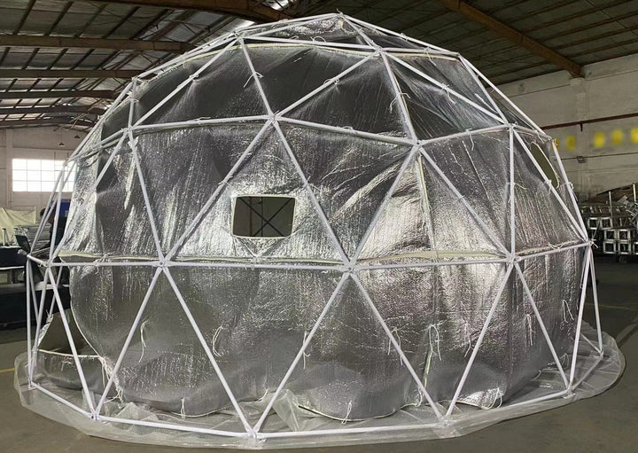 Geodesic dome tent by Glamping Dome Store in Calgary, Alberta, Canada, featuring a sturdy white powder-coated frame and reflective bubble foil insulation hanging inside the dome structure. The insulation includes a standard-size mesh-screen vent opening for improved air circulation and interior comfort.