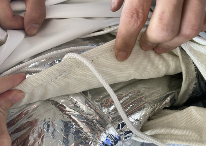 Close-up view of reflective bubble foil insulation finished with off-white canvas on the interior side of a geodesic dome tent by Glamping Dome Store. The image highlights the durable materials used for temperature regulation and comfort in a geodesic dome tent setup.